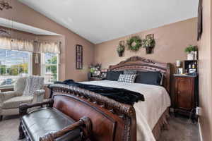 Carpeted room featuring a bay window with blinds, vaulted ceiling, and neutral wall tones