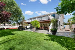 Expansive green lawn with mature trees and a two-story deck featuring white railings