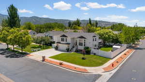 Contemporary two-story residence with a light-toned exterior and dark roof, situated on a corner lot