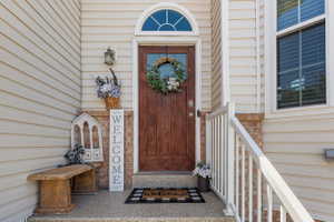 Front entry featuring a paneled wood door with an arched transom window, a brick facade accent, and light-colored siding