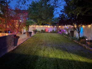 Manicured lawn area bordered by a stone-faced retaining wall and a white privacy fence