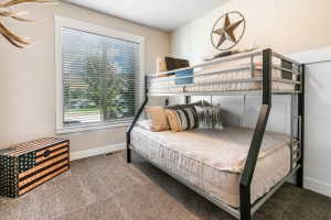 Spacious room featuring a large window with blinds, light-toned walls, and plush carpeting