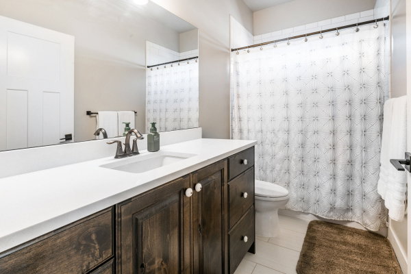 Bathroom vanity featuring a single integrated sink, white countertop, and dark wood-finish cabinetry