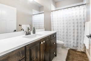 Bathroom vanity featuring a single integrated sink, white countertop, and dark wood-finish cabinetry