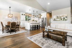 Open-concept living space featuring wood-finish flooring, a vaulted ceiling, recessed lighting, and a kitchen island with seating