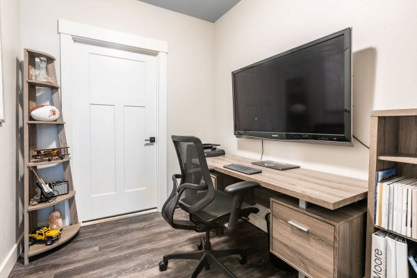 Dedicated workspace featuring wood-finish flooring, a contemporary built-in desk, and a modern interior door with matte black hardware
