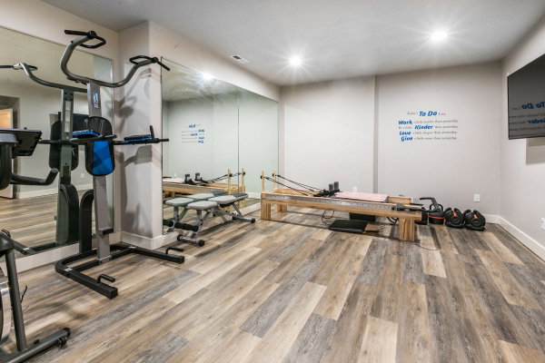 Spacious interior room featuring wood-finish flooring, recessed lighting, and expansive wall-mounted mirrors