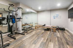 Spacious interior room featuring wood-finish flooring, recessed lighting, and expansive wall-mounted mirrors