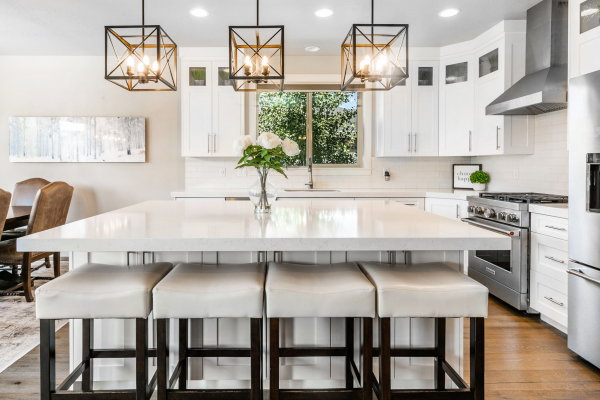 Contemporary kitchen featuring a large central island with seating, white shaker cabinetry, stainless steel appliances, and wood-finish flooring