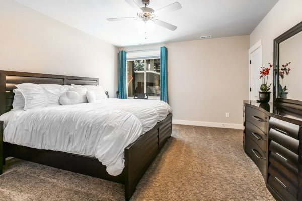 Carpeted bedroom featuring a ceiling fan, a window with exterior views, and neutral-toned walls