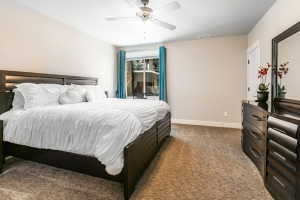Carpeted bedroom featuring a ceiling fan, a window with exterior views, and neutral-toned walls