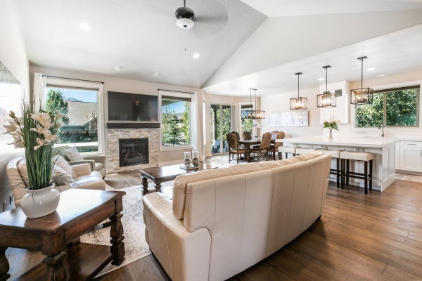 Vaulted ceilings enhance this open-concept living space, featuring a stone-surround fireplace with a wood mantel