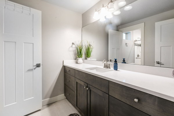Contemporary bathroom vanity featuring a light-colored countertop, an integrated sink with a brushed nickel faucet, and dark wood-finish cabinetry