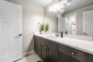 Contemporary bathroom vanity featuring a light-colored countertop, an integrated sink with a brushed nickel faucet, and dark wood-finish cabinetry