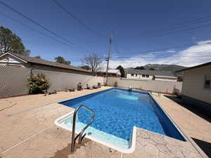 Inviting in-ground swimming pool featuring a bright blue liner and integrated steps, surrounded by stamped concrete decking