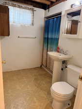Bathroom featuring a pedestal sink, white toilet, and a shower stall