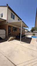 Rear exterior featuring brick and siding facade, covered patio, concrete patio space, and inground swimming pool