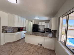 Kitchen featuring white cabinetry, stone-finish countertops, and tile flooring
