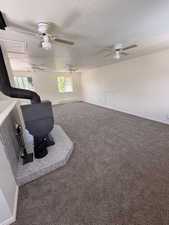 Spacious room featuring a central wood-burning stove with a tile hearth, multiple ceiling fans, and neutral-toned carpeting throughout