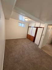 Carpeted room featuring a built-in storage unit with wood-finish drawers and cabinet doors, a single window, and a flush-mount ceiling light fixture