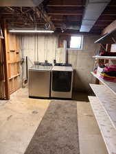 Dedicated laundry area featuring exposed concrete flooring, a floor drain, and overhead lighting