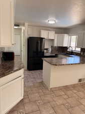 Kitchen featuring white cabinetry, patterned countertops, and a black appliance suite