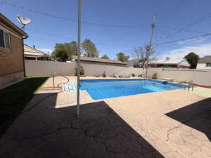 Backyard swimming pool featuring a diving board and entry steps with handrails