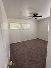Spacious room featuring neutral carpeting, white walls, and a modern ceiling fan with integrated lighting