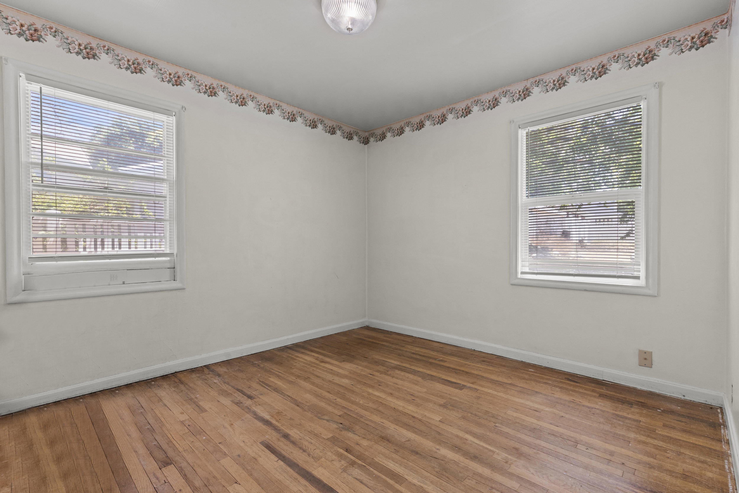 Hardwood flooring throughout, complemented by two windows with horizontal blinds
