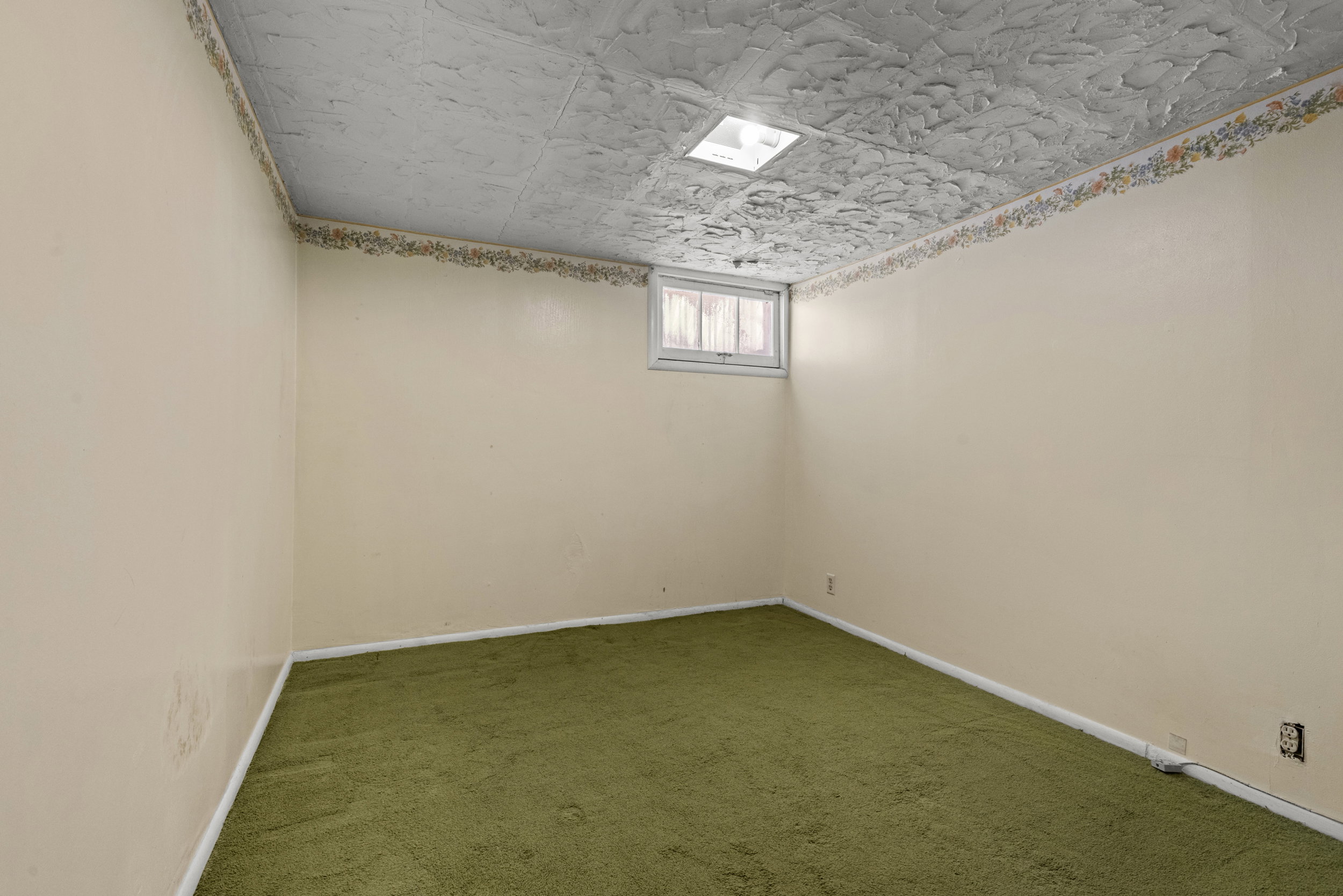Room featuring textured ceiling, light-colored walls with decorative border, and green carpeting