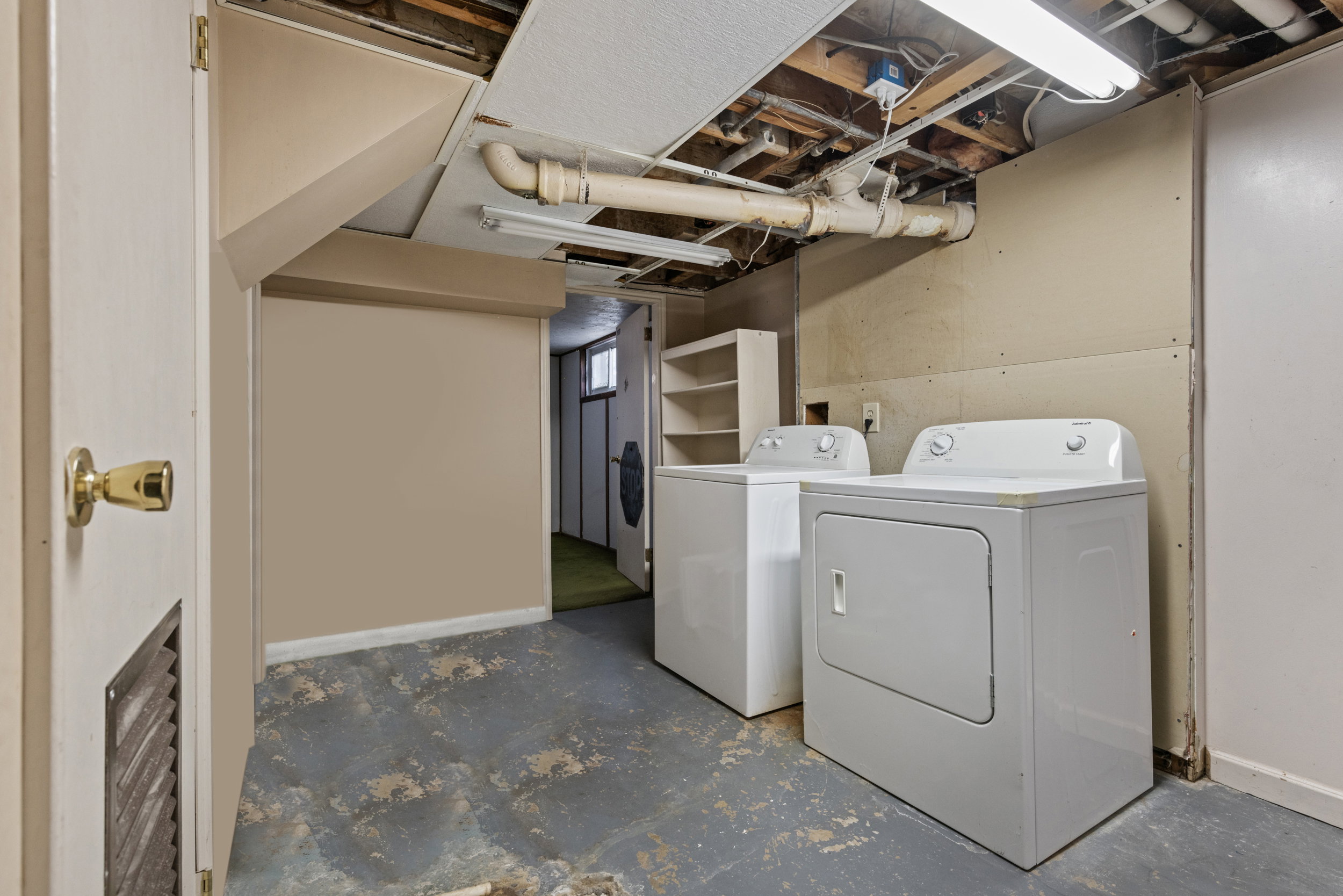 Utility area featuring a washer and dryer, exposed ceiling joists, overhead fluorescent lighting, and a partial dropped ceiling