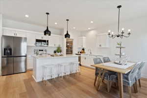 Modern kitchen featuring white cabinetry, stainless steel appliances, a central island with bar seating, and wood-finish flooring