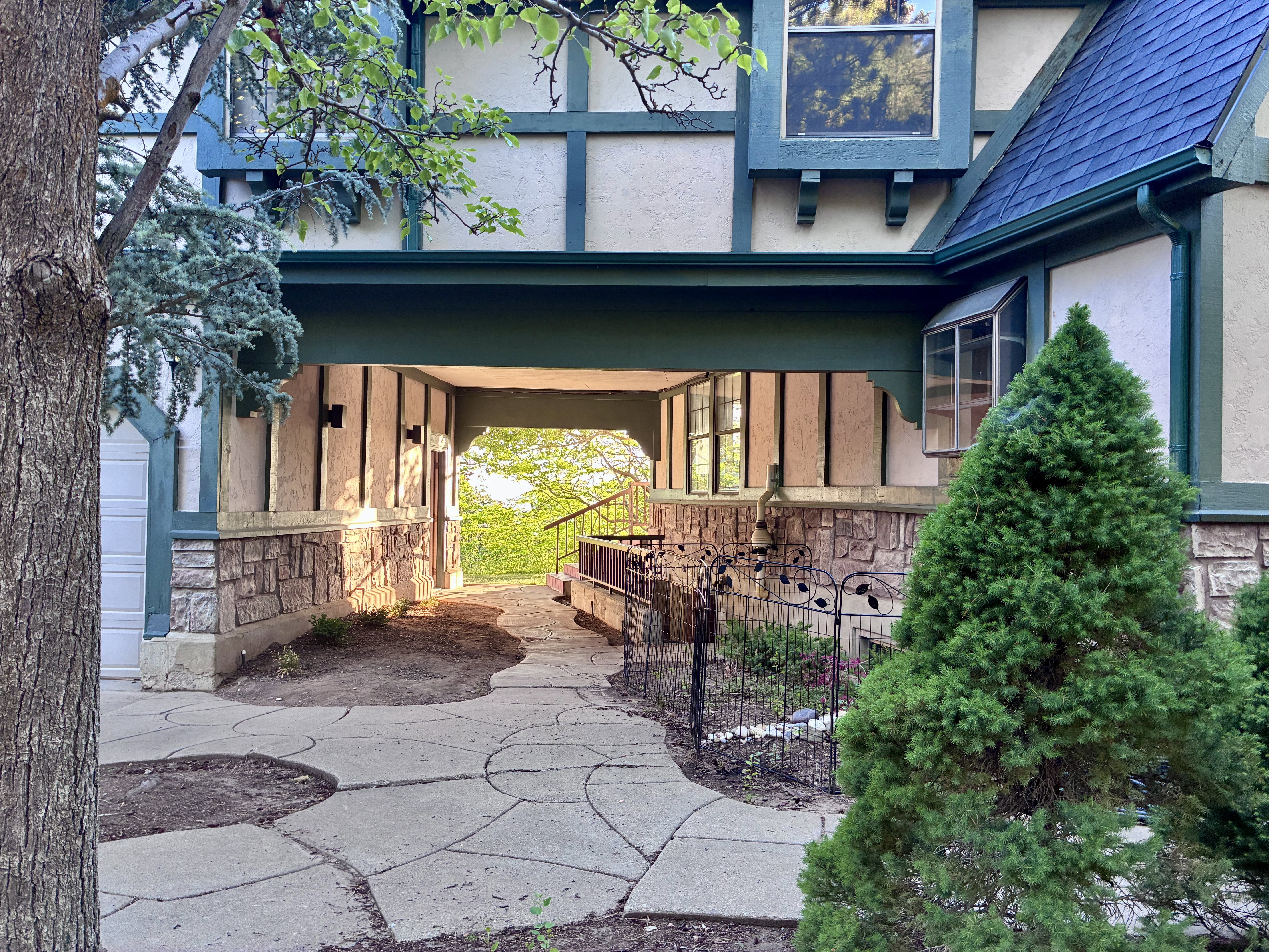Tudor-style exterior showcasing a prominent stone foundation, half-timber detailing, and a blue shingle roof