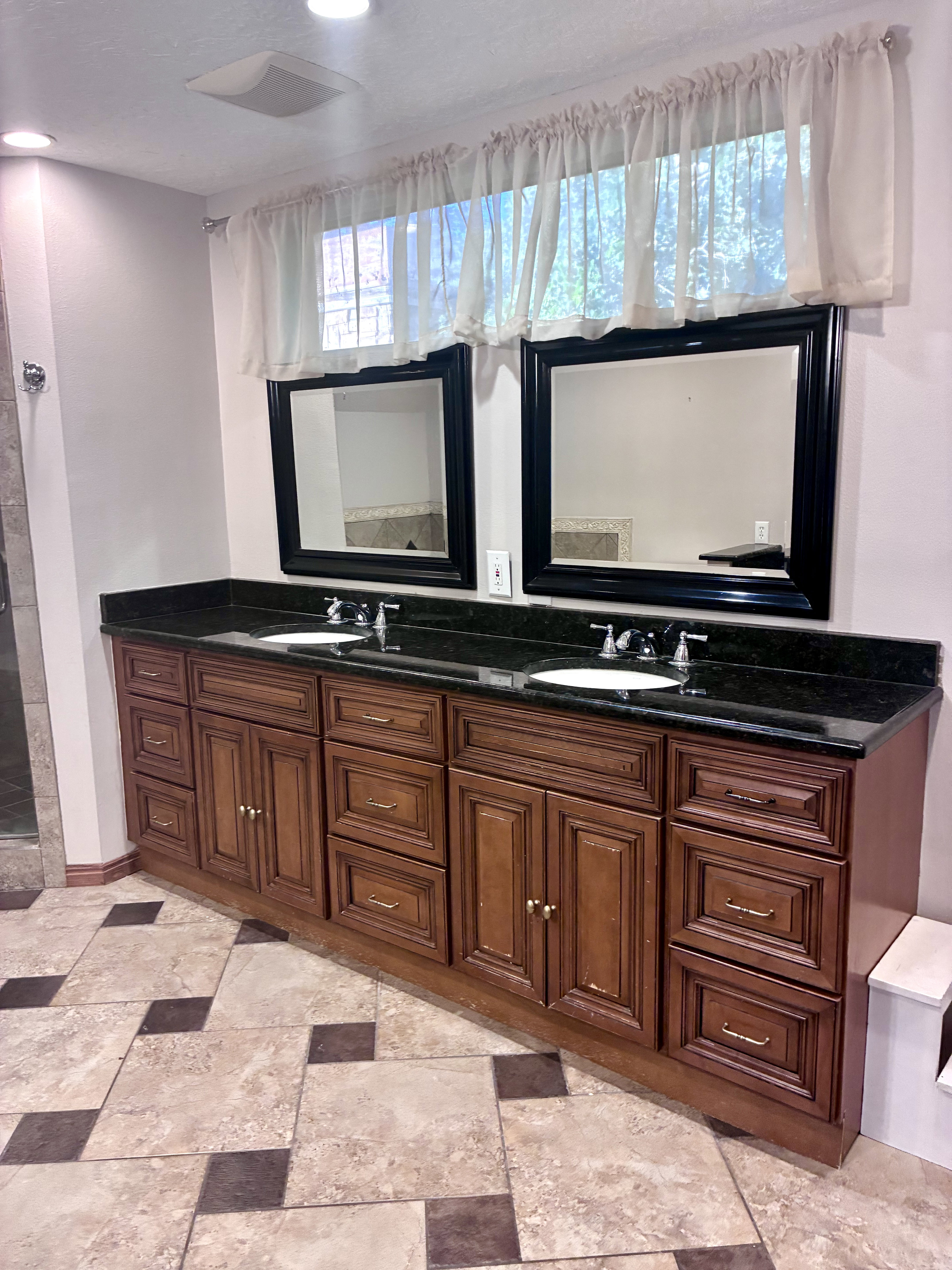 Dual vanity featuring dark wood cabinetry, black countertops, and two undermount sinks
