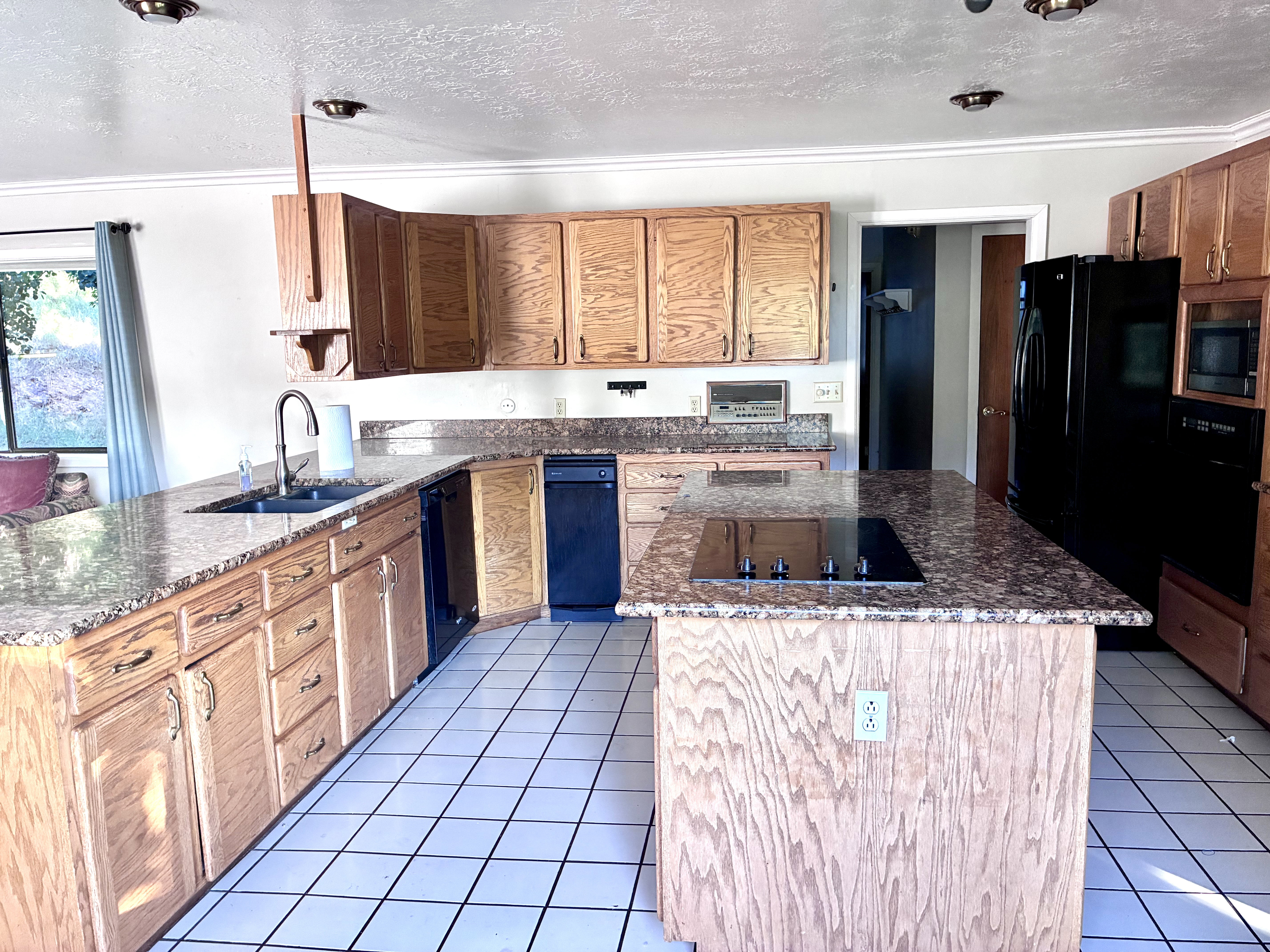 Kitchen featuring light wood cabinetry, granite-finish countertops, and white square tile flooring