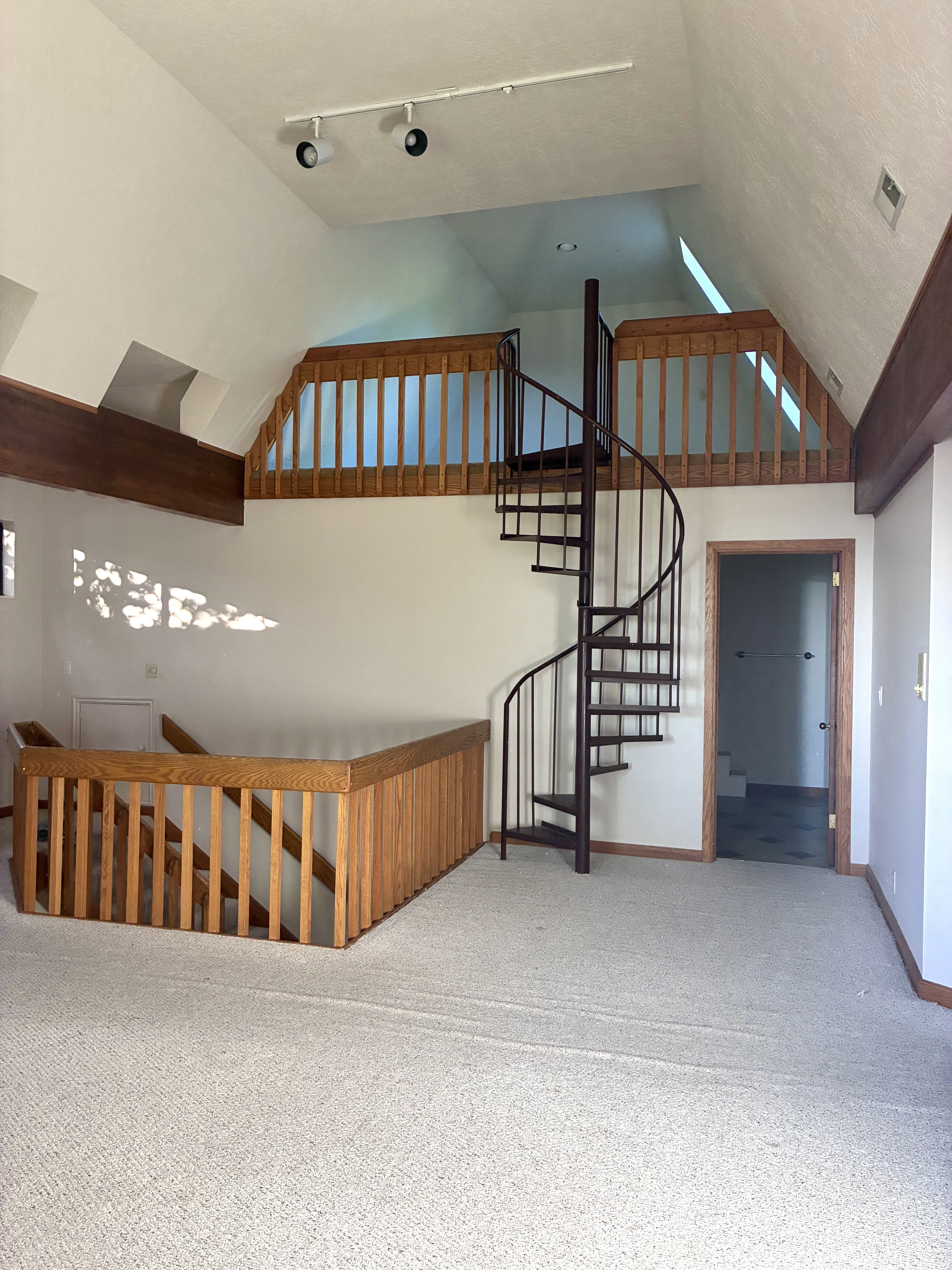 Interior space featuring a spiral staircase, vaulted ceiling, and track lighting