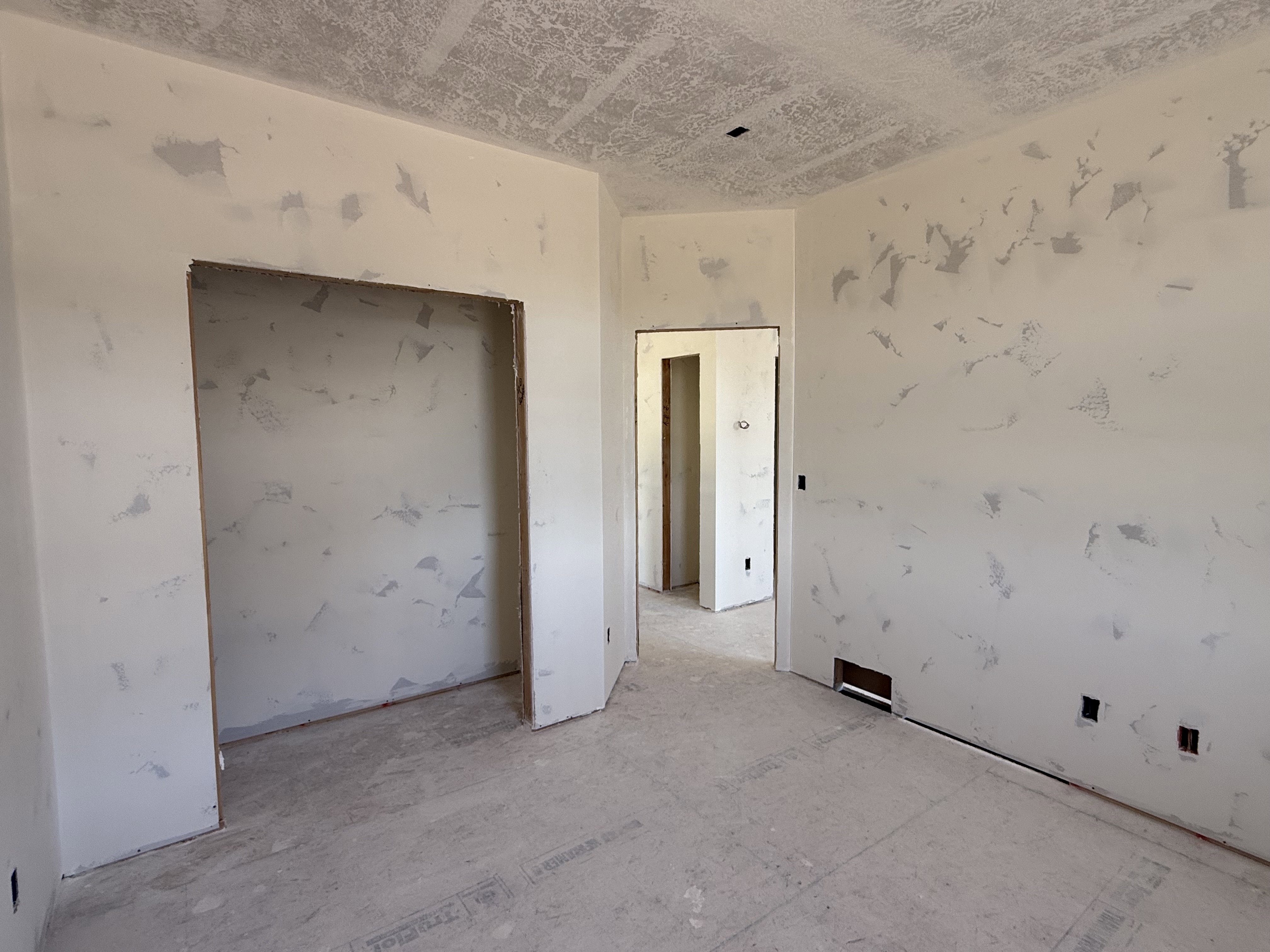 Unfinished interior space featuring light-toned walls and a textured ceiling
