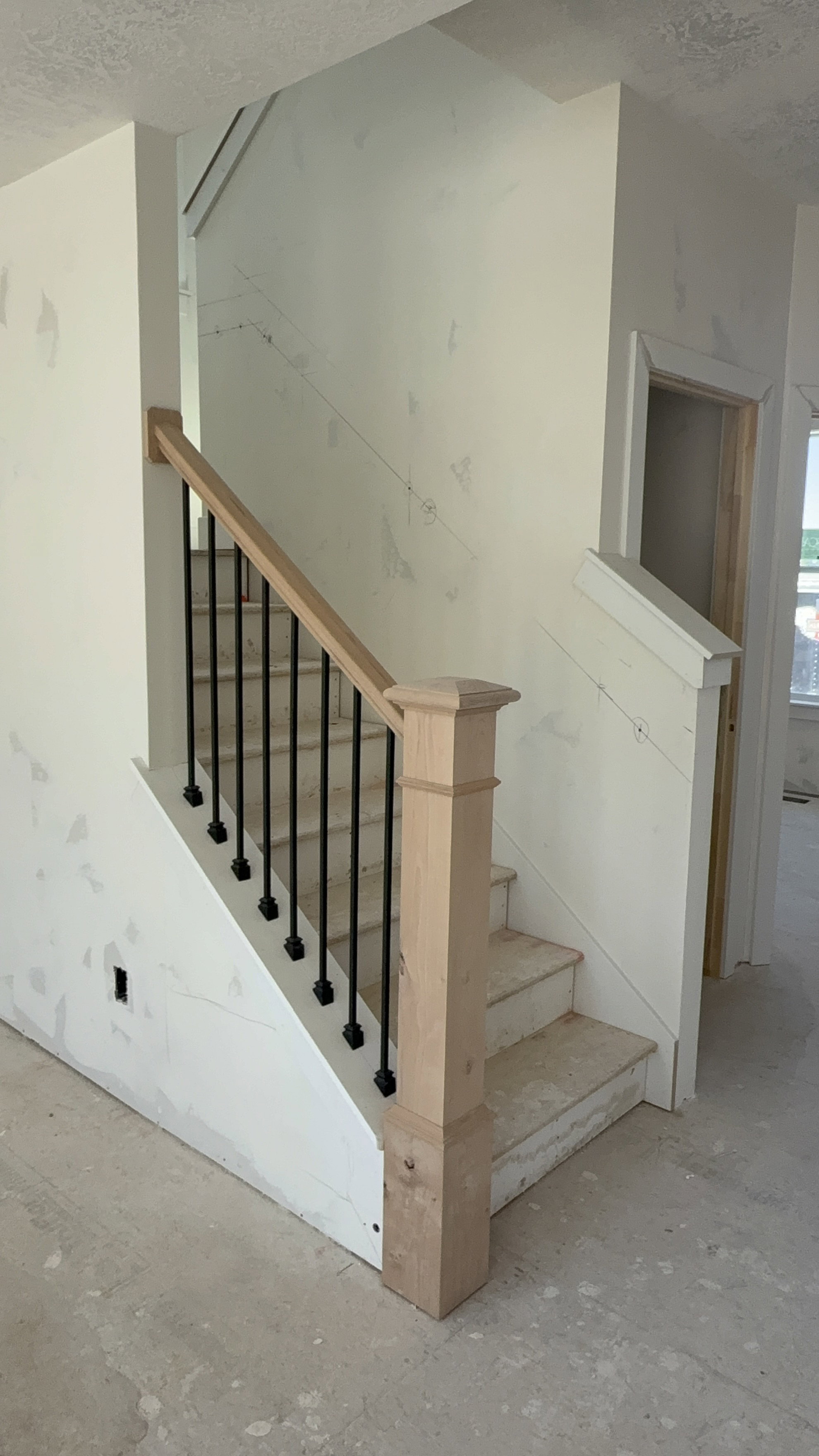 Staircase featuring wood newel post and handrail with black iron balusters