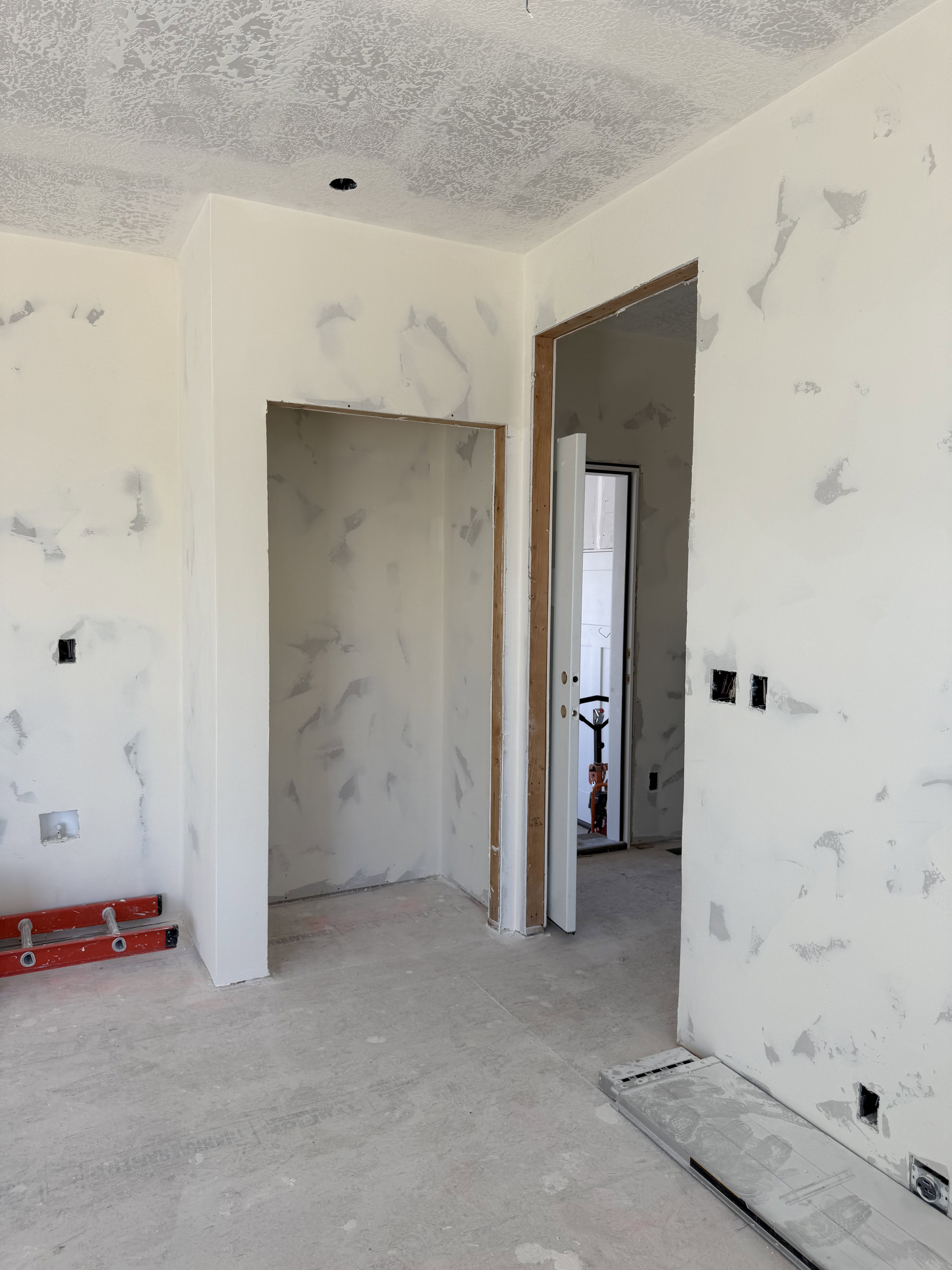 Interior space under construction featuring a doorway with wood framing, a recessed wall niche, and concrete flooring