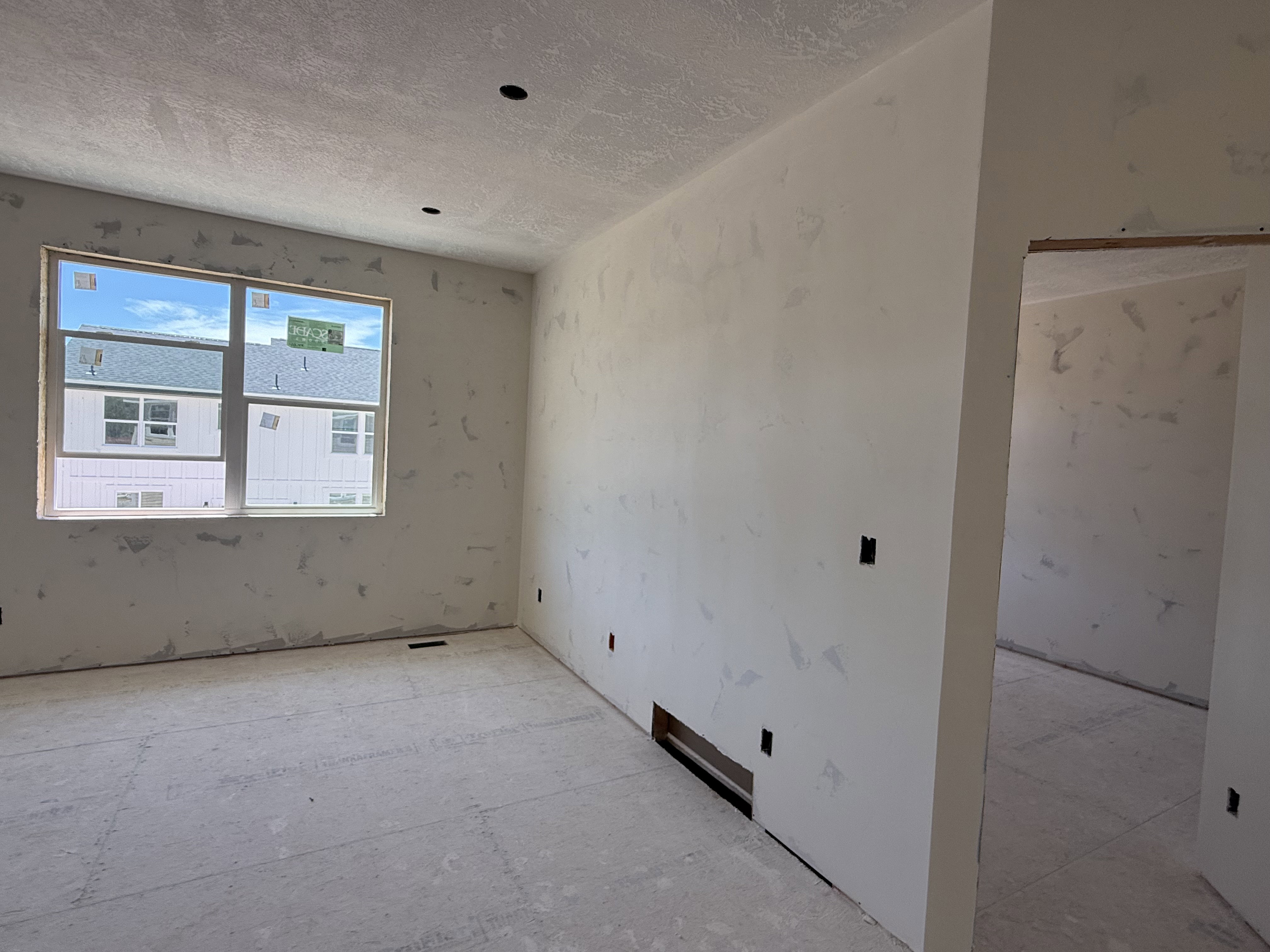 Unfinished interior room featuring a large window, recessed lighting, and an open doorway
