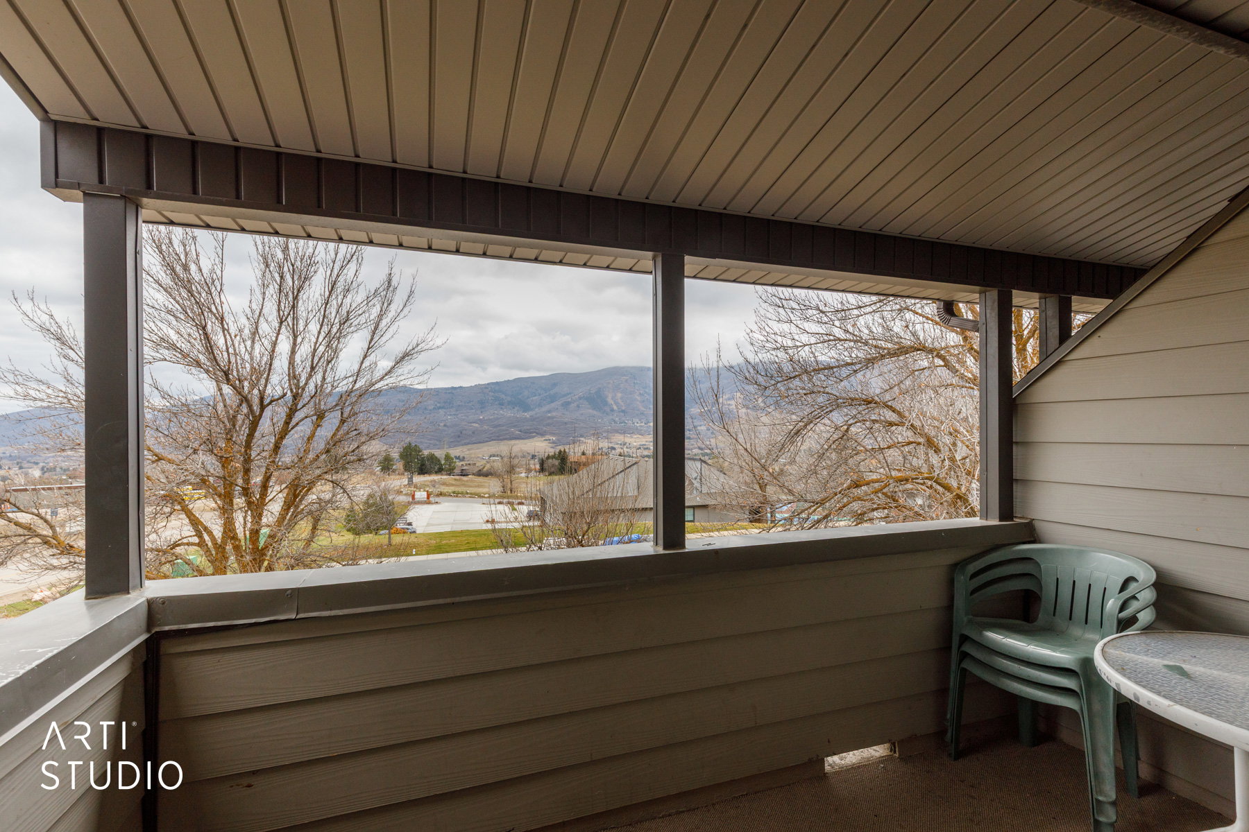 Covered balcony with a slatted ceiling, dark support beams, and mountain scenery