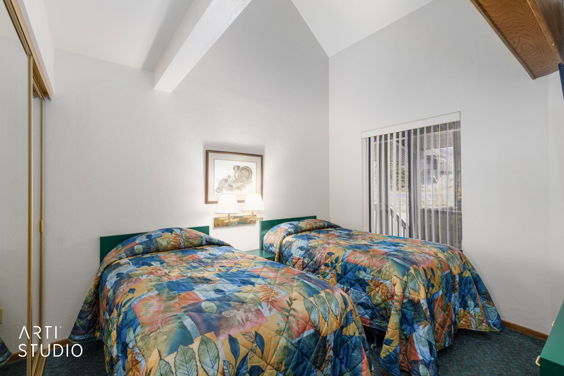 Room featuring vaulted ceilings with exposed wood beams, a wall-mounted light fixture, sliding glass doors with vertical blinds, and a mirrored closet