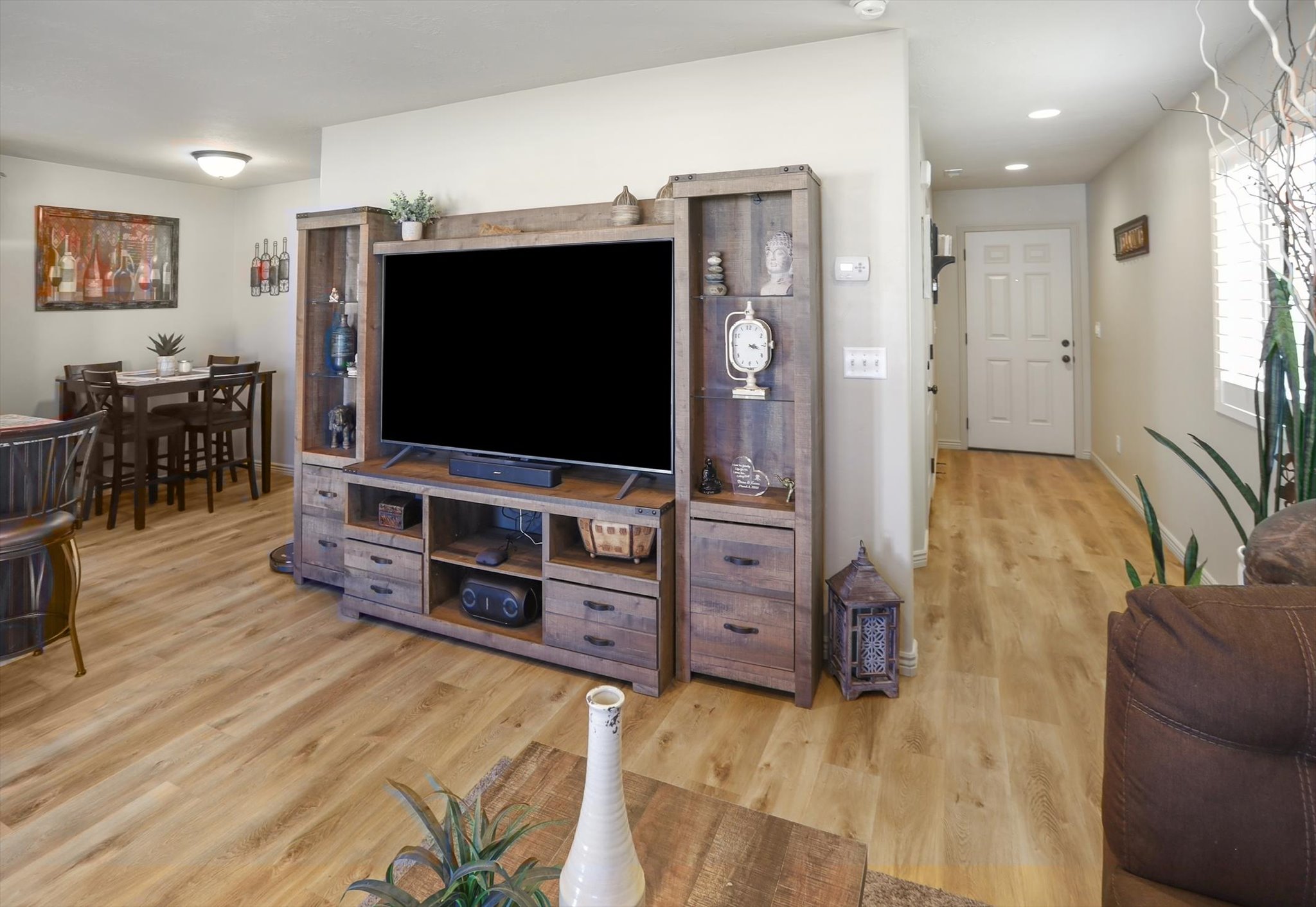 Open-concept living space featuring wood-finish flooring, recessed lighting, and a white six-panel entry door