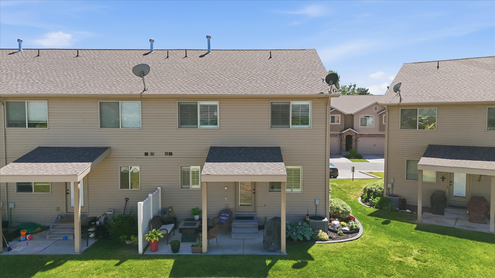 Rear exterior featuring a covered patio, manicured lawn, and landscaped garden beds