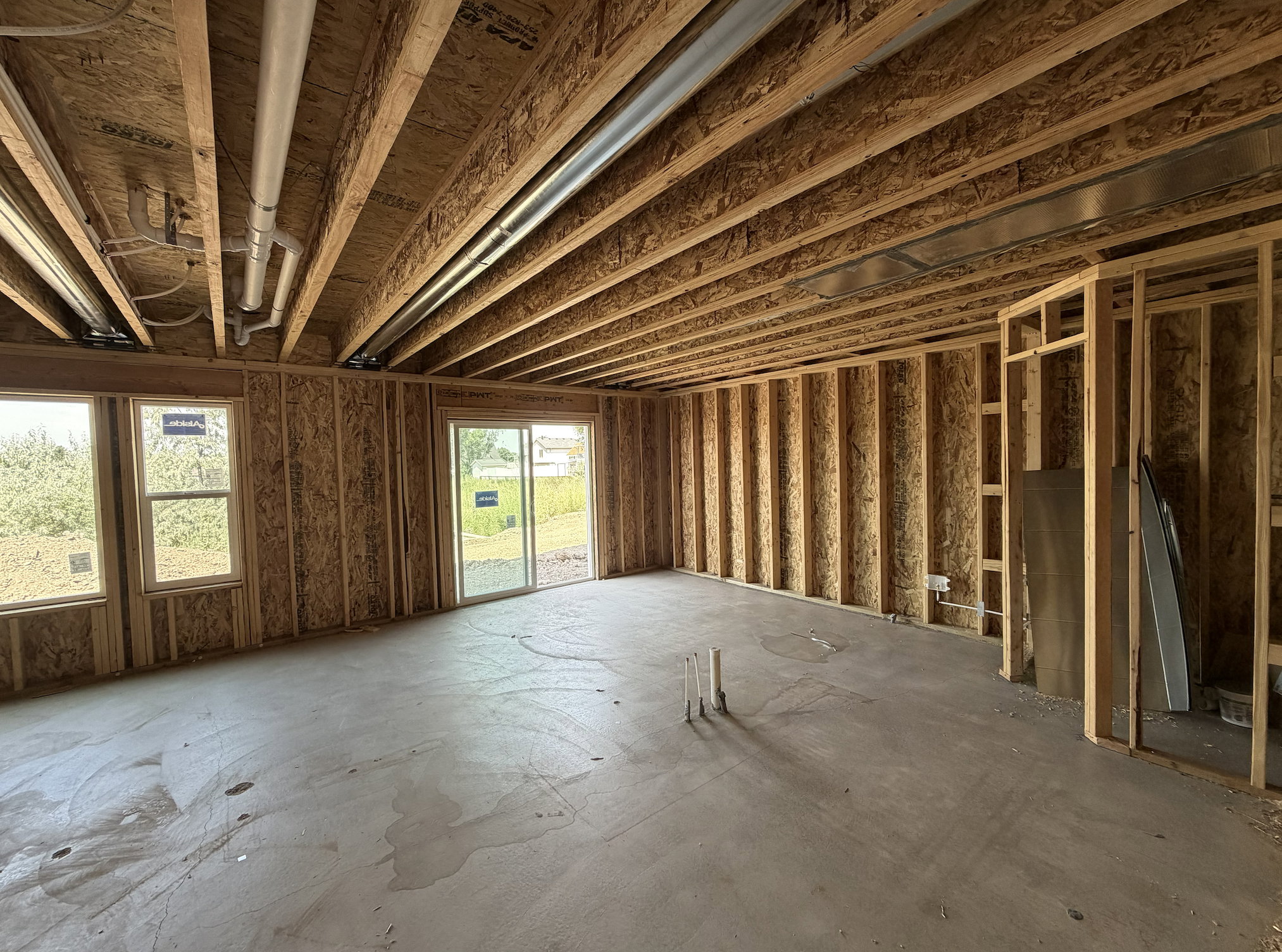 Unfinished interior space with exposed wood framing, a concrete floor, and multiple windows