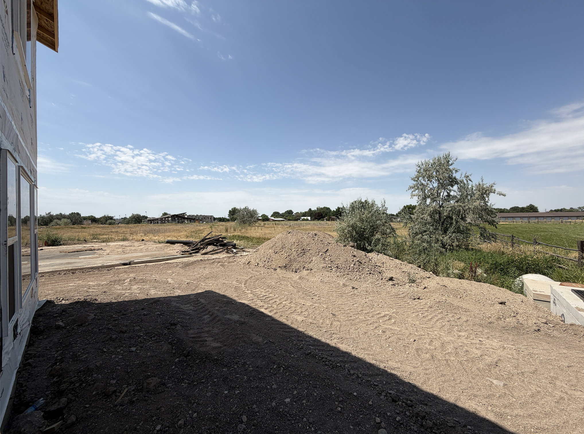 Expansive exterior space with clear sky, partial building framing, and surrounding open fields