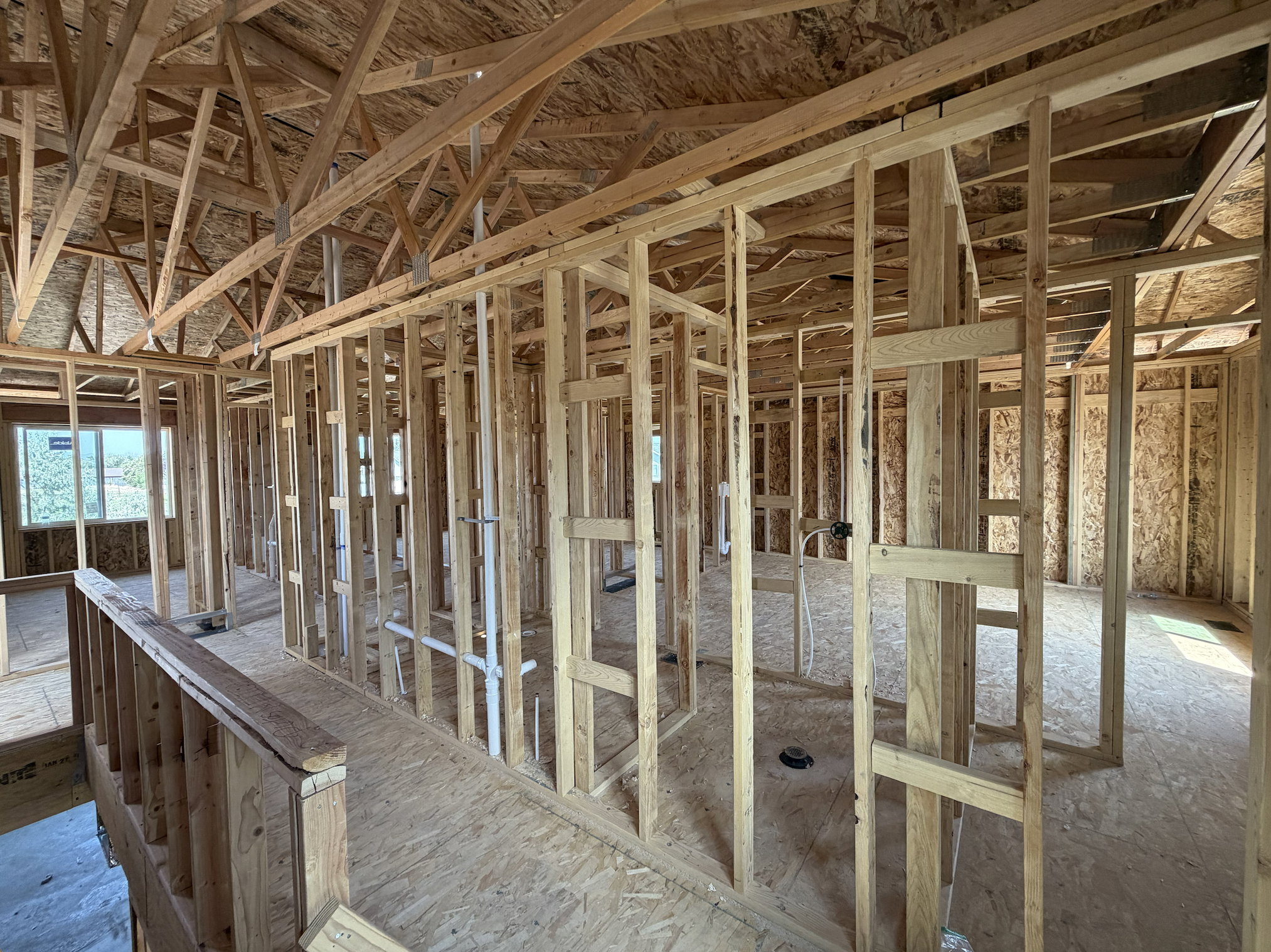 New construction framing with visible structural elements, rough plumbing, and window openings