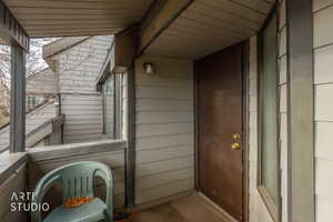 Covered entry porch featuring a solid brown entry door with brass hardware and a textured glass sidelight