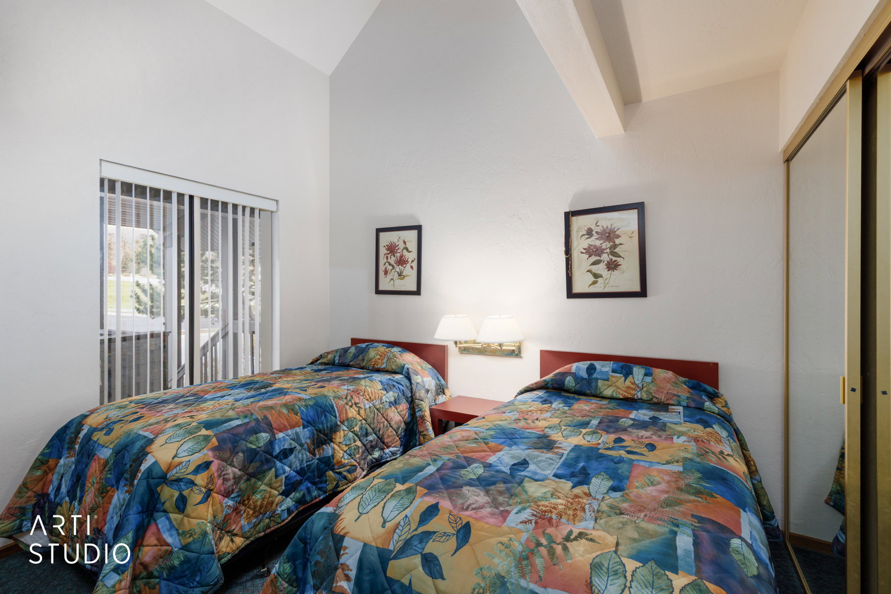 Vaulted ceiling room featuring a sliding glass door with vertical blinds, wall-mounted lighting, and mirrored closet doors