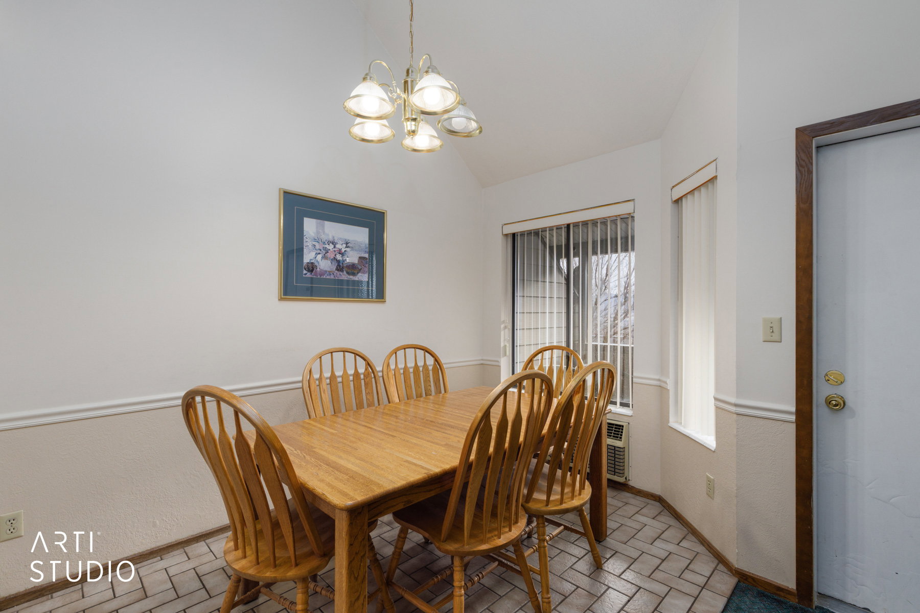 Dining area featuring a vaulted ceiling, patterned tile flooring, and wainscoting